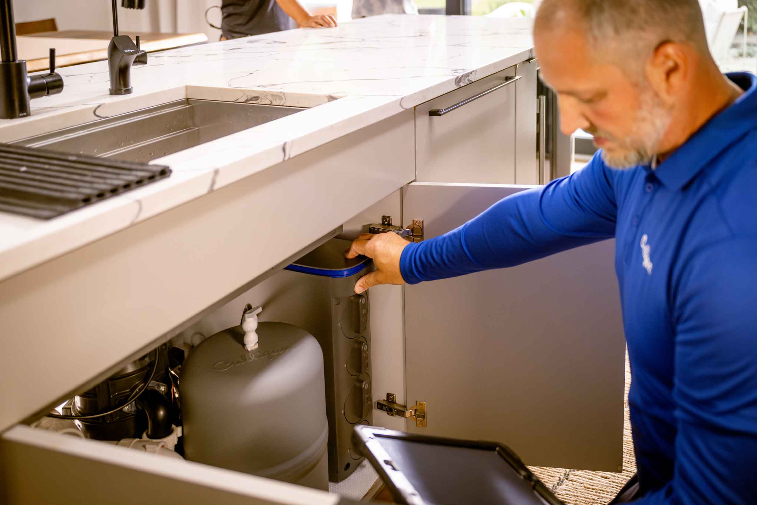 Culligan man checking water filter under kitchen sink.